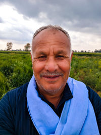 Portrait of smiling man on field against sky