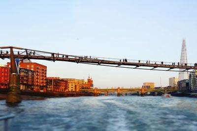 Bridge over river in city against clear sky