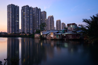 Buildings by city against sky at dusk