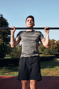 Young man doing pull-ups on pull-up horizontal bar during his workout in a calisthenics park