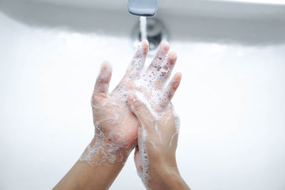 Cropped image of person washing hands in sink