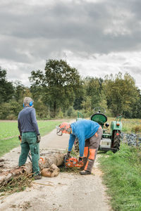 Rear view of people working on dirt road