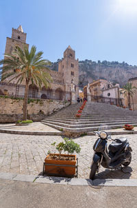 Few people around duomo di cefalù with rocca di cefalù in sicily - copy space, angled view.