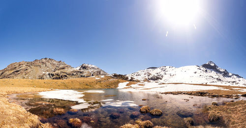 Scenic view of snowcapped mountains against blue sky on sunny day