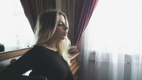 Young woman standing by window at home