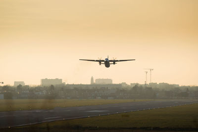 Airplane flying in sky at sunset