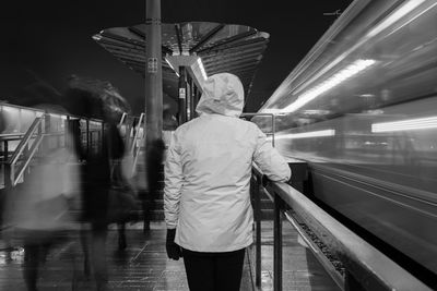 Rear view of woman standing by railing in city at night