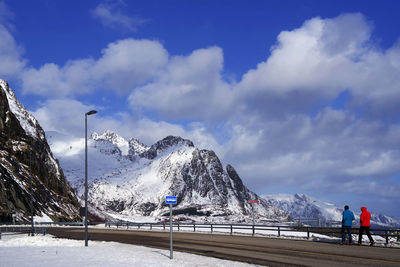 People on snowcapped mountain against sky