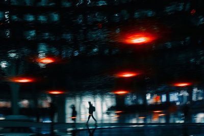 Blurred motion of man walking on illuminated city street at night