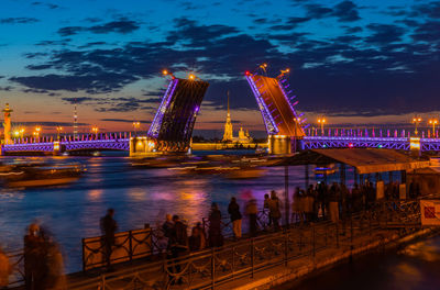 Illuminated bridge over river against sky at night