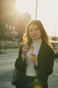 Portrait of beautiful woman holding flavored ice in city