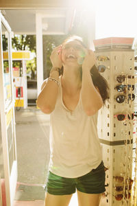 Cheerful woman trying sunglasses at gas station