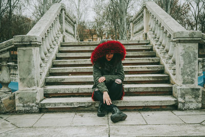 Full length of woman sitting on staircase