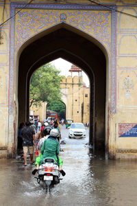 People on wet street amidst buildings in city