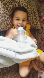 Portrait of cute boy drinking glass on bed