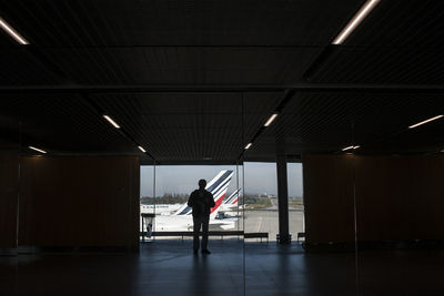 Rear view of man walking in illuminated building