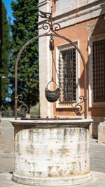Ancient metal structure over a  water well against building in city