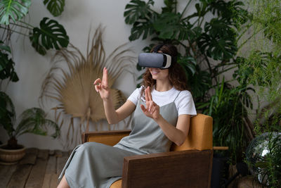 Curious woman in virtual reality glasses interacting with objects in interactive immersive world