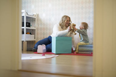 Rear view of woman sitting on hardwood floor at home