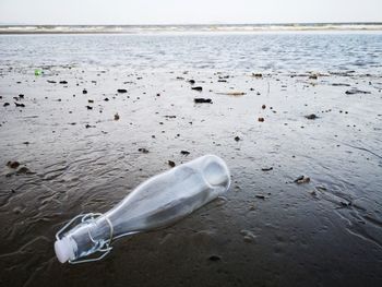 Water bottle on sand at beach against sky