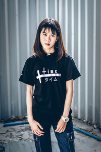 Portrait of beautiful young woman standing against wall