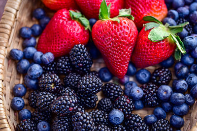 Woven basket of red strawberries, blueberries, and blackberries