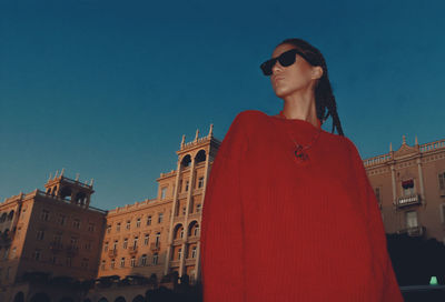 Portrait of woman wearing sunglasses standing against clear sky