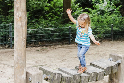 Full length of girl walking on wooden play equipment at playground