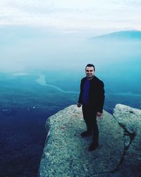 Full length portrait of man standing on cliff