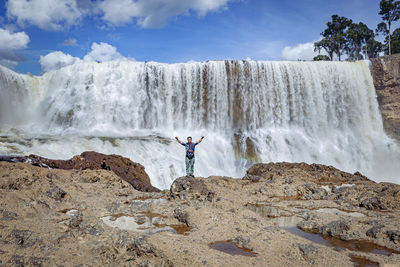 Man standing on rock against waterfall