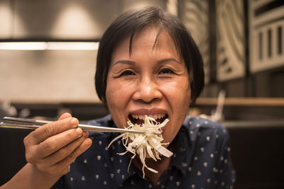 Close-up portrait of woman eating food at restaurant