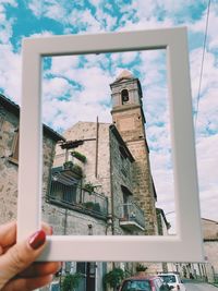 Midsection of person holding umbrella against sky