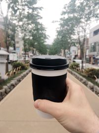 Close-up of hand holding cup of building