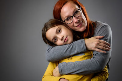 Portrait of mother and daughter against gray background