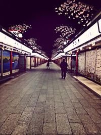 Full length of woman walking on illuminated walkway at night