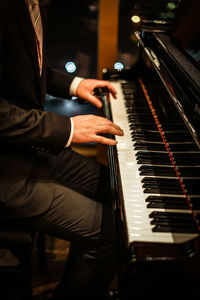 Midsection of man playing piano