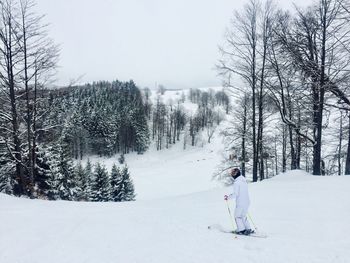 Man skiing on snowy field against sky during winter