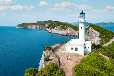 Lighthouse by sea against sky