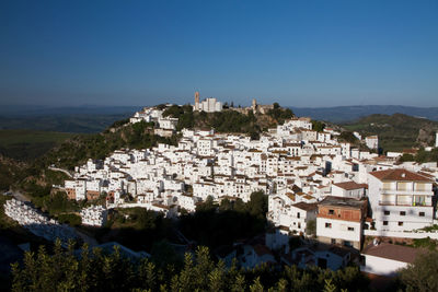 High angle view of houses in town against clear blue sky