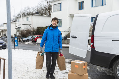 Smiling essential service woman delivering paper bags during winter