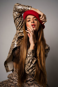 Portrait of young woman wearing hat against gray background