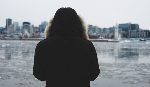 Rear view of woman standing by river in city