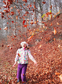 Happy girl playing with leaves in autumn