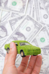 Cropped hand of man holding toy car over paper currency