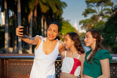 Tourists taking a selfie at a bridge on the cali river boulevard with la ermita church on background