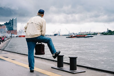 Rear view of man standing on boat port with hand luggage