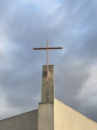 Low angle view of cross on building against sky