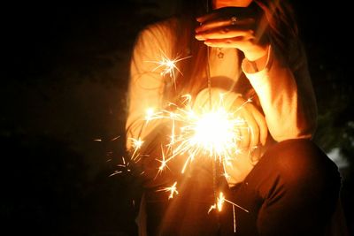 Close-up of woman holding sparkler at night