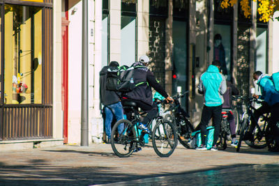 Rear view of people riding bicycle on street