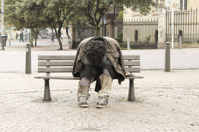 Full length of man sitting on bench in park